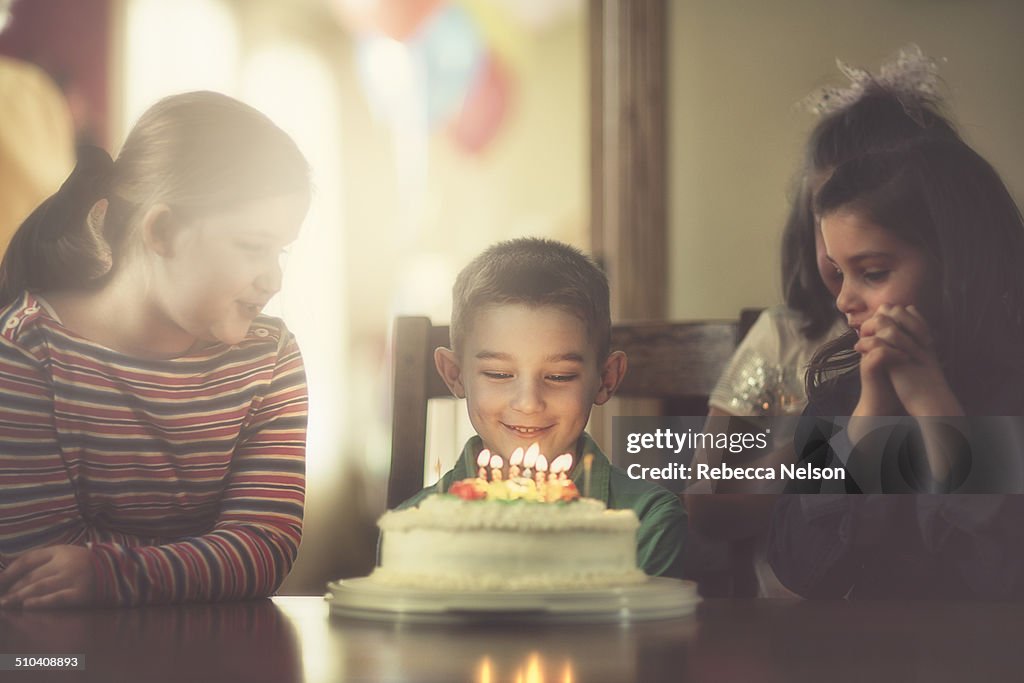 Children gathered around boy with birthday cake