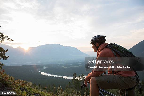 mountain biker takes break to watch sunrise, mtns - one man only stock pictures, royalty-free photos & images