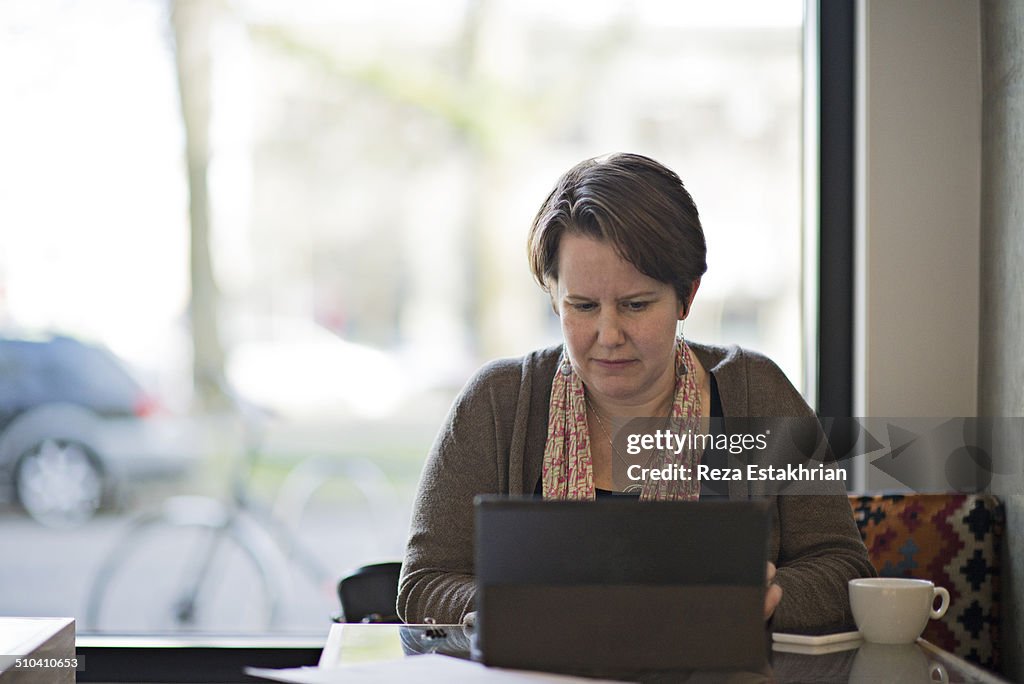 Woman works on laptop in cafe