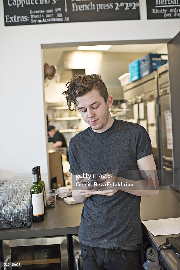 Waiter checks cell phone during work break