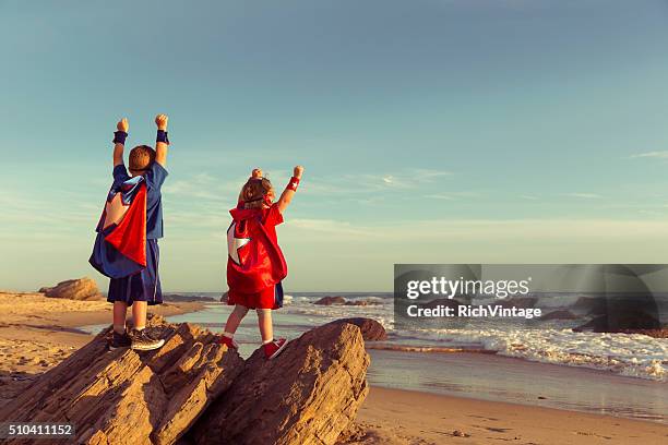 boy and girl dressed as superheroes on california beach - superhero girl stock pictures, royalty-free photos & images