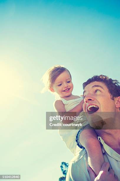 father giving his daughter a piggy back ride. - father sun stock pictures, royalty-free photos & images