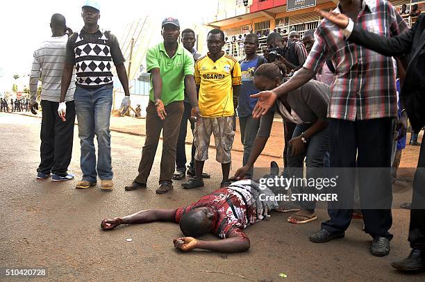 Graphic content / People gather around the body of man on a Kampala street on February 15 after he was allegedly killed during clashes between police...