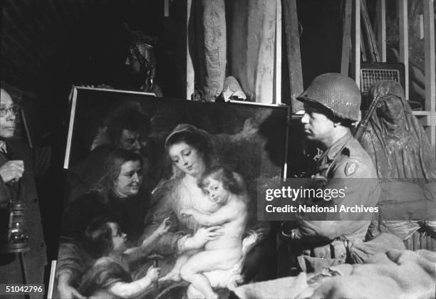 Tony Baea of the U.S. First Army, holding a Rubens painting looted by the Nazis and one of many valuable works found in an underground cave in...