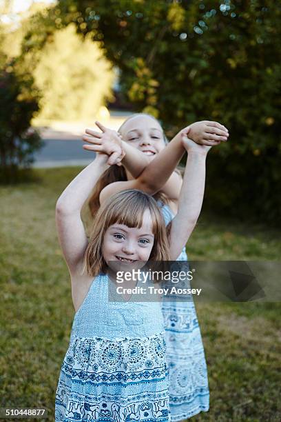 Sisters in blue dresses playing in yard.