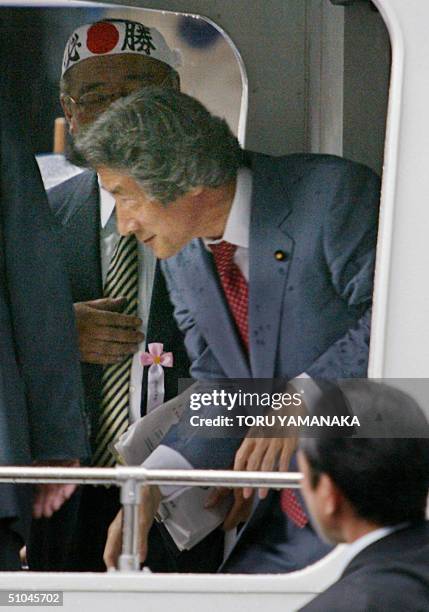 Japanese Prime Minister Junichiro Koizumi walks past a man wearing a headband printed with a rising sun during a stumping tour in Tokyo, 10 July...