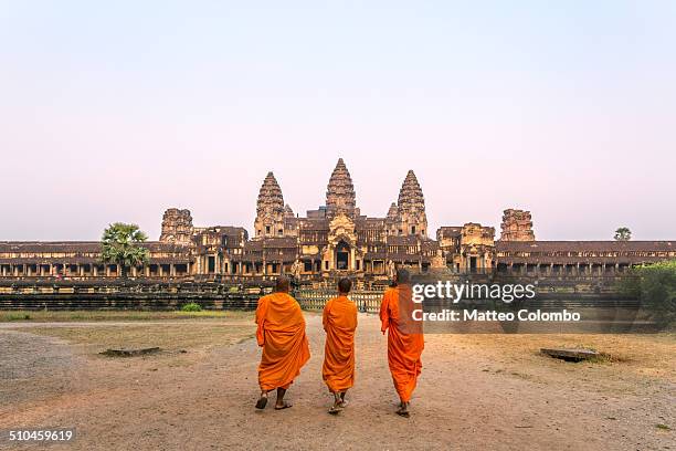 three buddhist monks walking to angkor wat temple - camboya fotografías e imágenes de stock