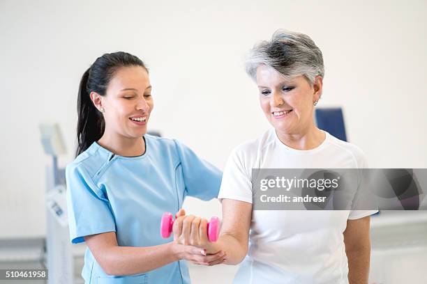 senior woman in physiotherapy for her wrist - carpaletunnelsyndroom stockfoto's en -beelden