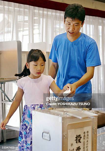 Girl helps her father cast vote for the Upper House election at a Tokyo polling station, 11 July 2004. Japanese voters expected to deliver a verdict...