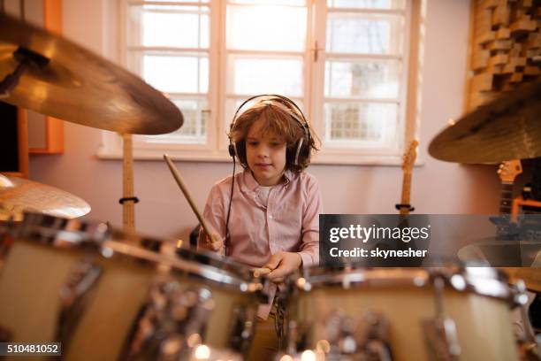 little boy wearing headphones and playing drums. - drum stockfoto's en -beelden