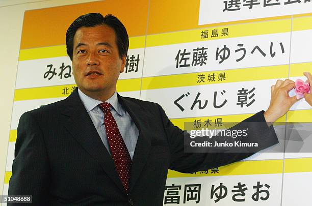 Democratic Party of Japan leader, Katsuya Okada, places a flower on the name of a victorious party member in elections for the Upper House of...