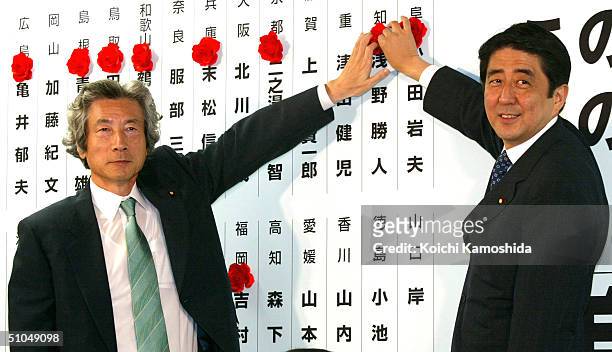 Japanese Prime Minister Junichiro Koizumi and Shinzo Abe , secretary-general of the ruling Liberal Democratic Party put paper roses on the names of...