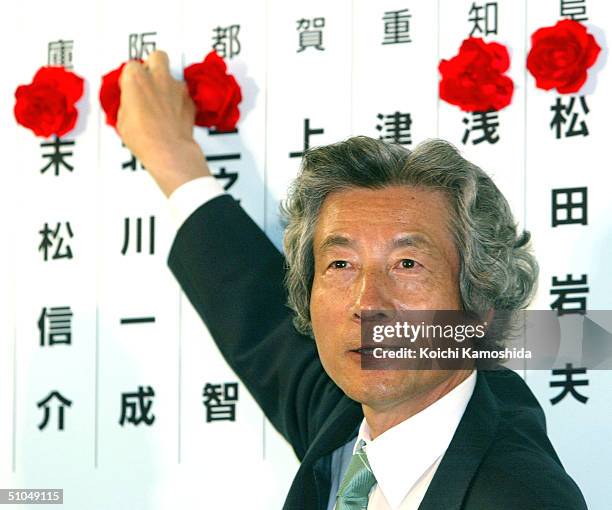 Japanese Prime Minister Junichiro Koizumi puts a paper rose on the name of a candidate reportedly elected in the Upper House election at the...