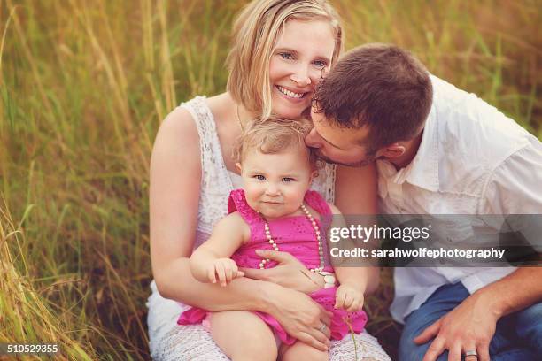 man leaning over to kiss daugher's head - mother and daugher together in a field stock pictures, royalty-free photos & images