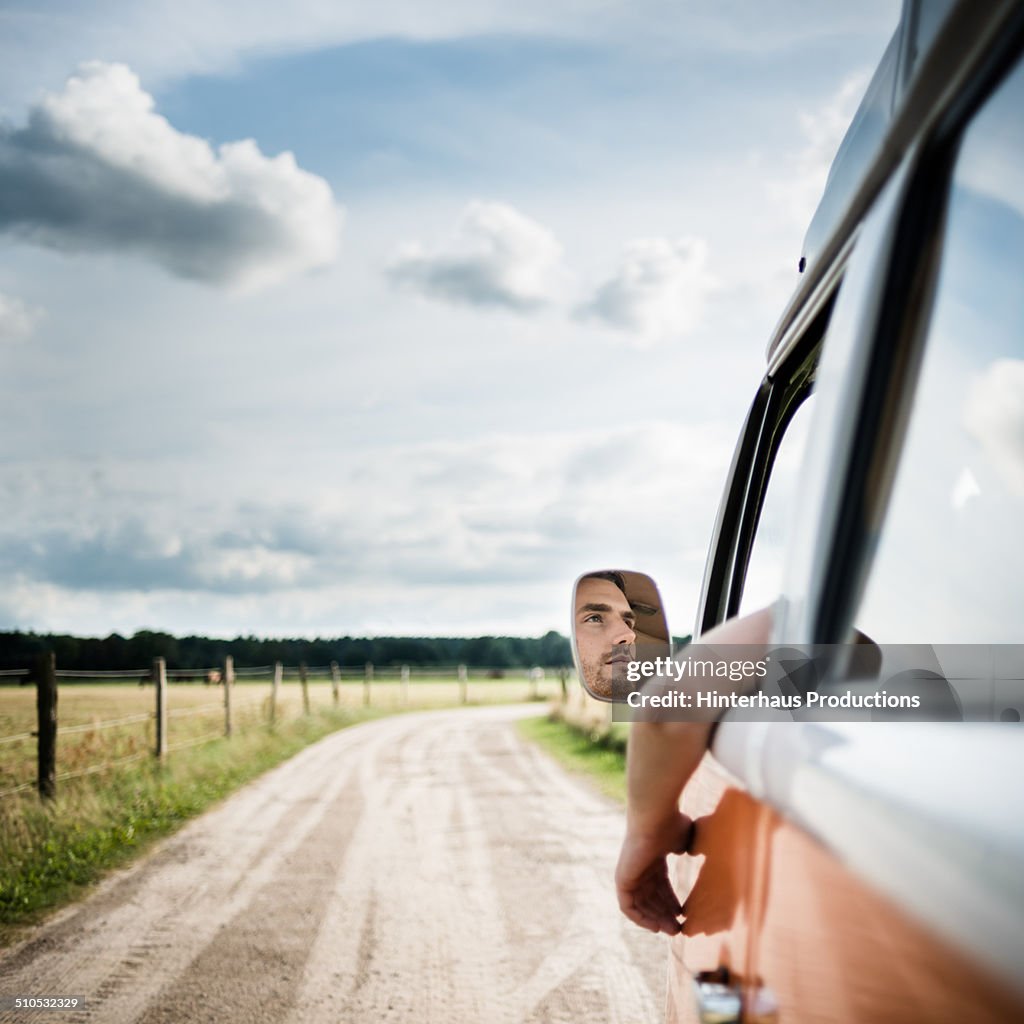 Man In Mirror Of A Bus On Country Road