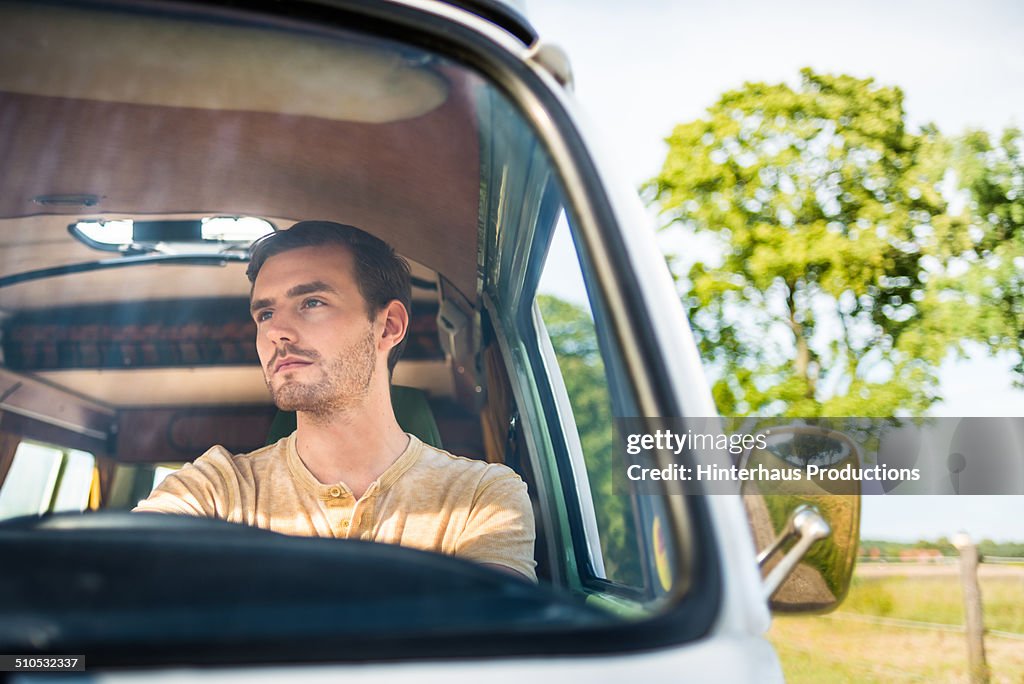 Young Man Driving Old Bus On Country Road