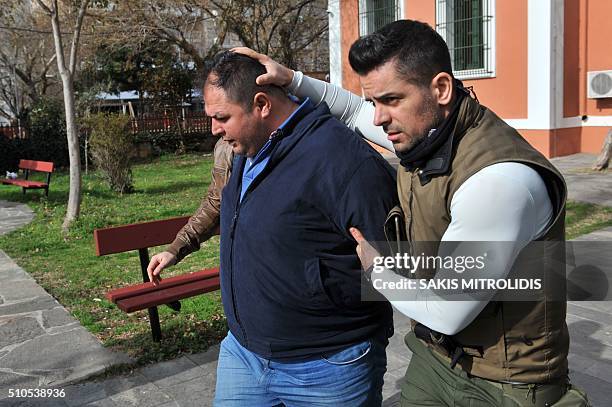 Policemen escort to the Alexandroupolis courthouse one of the three heavily armed Britons arrested near the border with Turkey where they were...