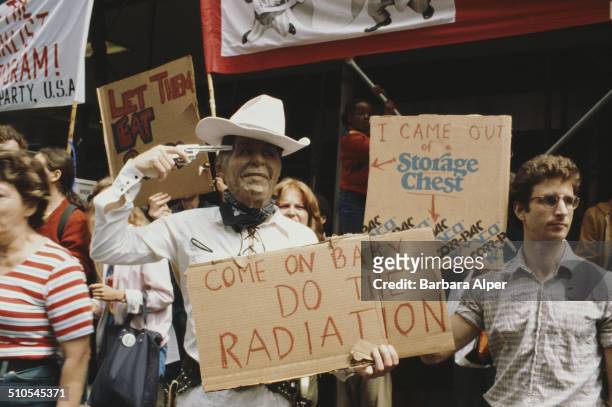 An anti-nuclear rally in Central Park, New York City, 12th June 1982. One protestor wears a Ronald Reagan mask and holds a gun to his head, whilst...