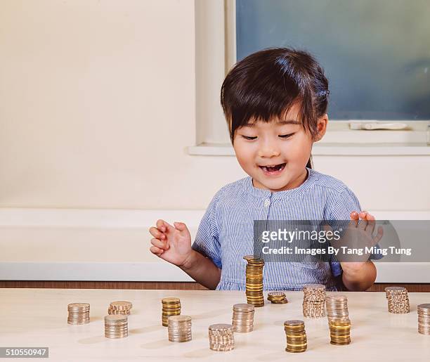 child stacking coins joyfully on table at home - chinese currency stock-fotos und bilder