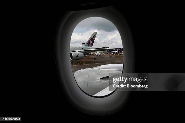 An Airbus A380 aircraft, operated by Qatar Airways Ltd., sits on the tarmac seen through the window of an Airbus A350 XWB aircraft operated by the...