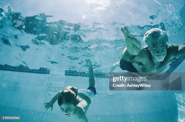 grandpa and grandson swimming underwater in summer - seniors having fun with grandson stockfoto's en -beelden