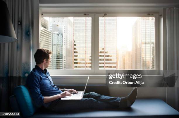 homem usando computador portátil - divã sofá imagens e fotografias de stock