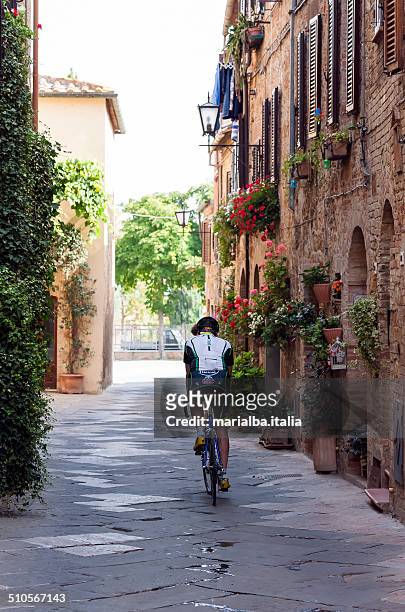 cyclist along an alley in pienza - siena italia 個照片及圖片檔