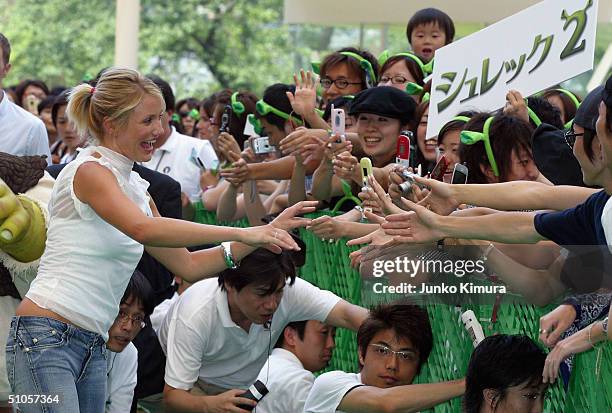 Actress Cameron Diaz shakes hands with youngsters who welcomed her at an event to promote a film "Shrek 2" on July 14, 2004 in Tokyo, Japan. The film...