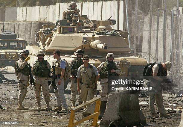 Army tank stands at the site where US Army personnel record evidence after a car bomb exploded at the main checkpoint for vehicles entering the Iraqi...