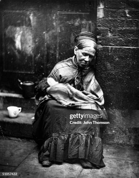 Beggar paid to look after a baby sitting at the side of a street, circa 1877. From 'Street Life in London' by John Thomson and Adolphe Smith - pub....