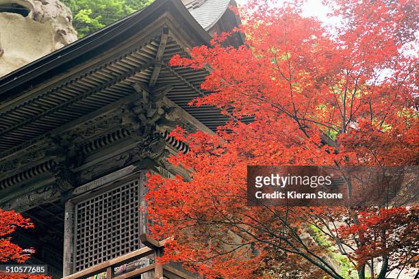 Temple at Yamadera with red autumn tree in the foreground.