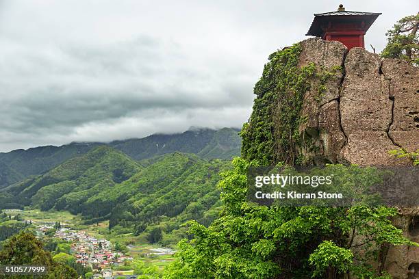 View of Nokyodo building on top of a cliff on the mountainside with views of the town in the valley below, Yamagata, Japan