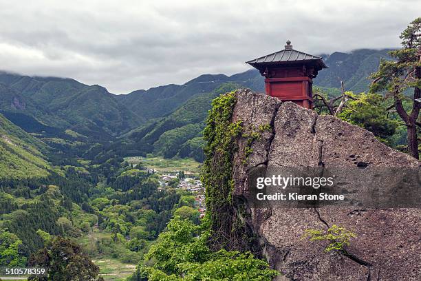 View of Nokyodo building on top of a cliff on the mountainside with views of the town in the valley below, Yamagata, Japan
