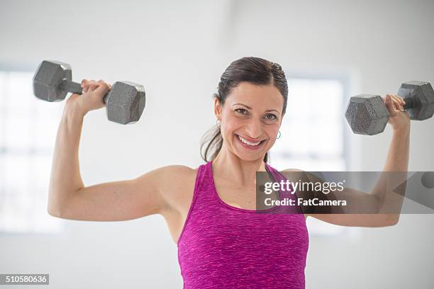 lifting dumbbells at the gym. - woman curled up stock pictures, royalty-free photos & images