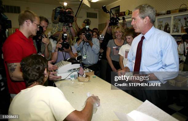 President George W. Bush buys a bag of bear claws, during an impromptu stop on his Bus campaign tour at the Mick's Candyman store 14 July in West...