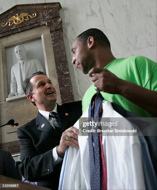 Congressman Wally Herger , Chairman of the Ways and Means Subcommittee on Human Resources, hands Darnell Wainweright a suite during a clothes drive...