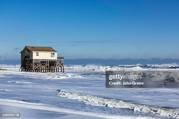 Beach house on stilts surrounded by high tide surf.