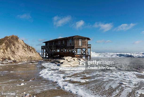 Beach house on stilts surrounded by high tide surf.