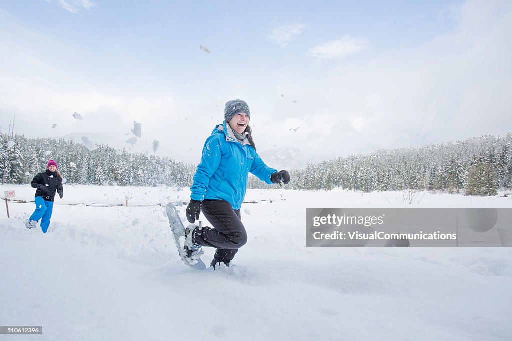 Eine Gruppe von Freundinnen Schneeschuhwanderungen und hat gute Schneeballschlacht.