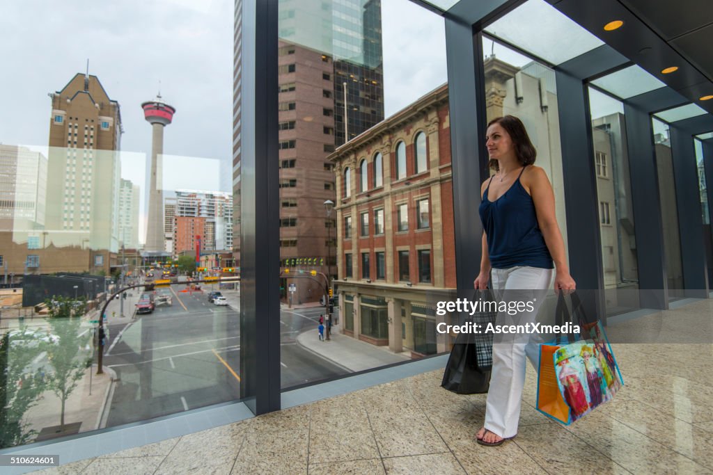 Woman carries shopping bags on pedestrian walkway