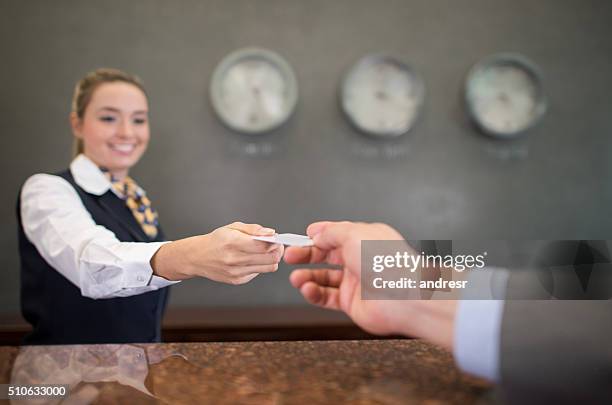 woman working at a hotel handing a loyalty card - loyalty cards stock pictures, royalty-free photos & images