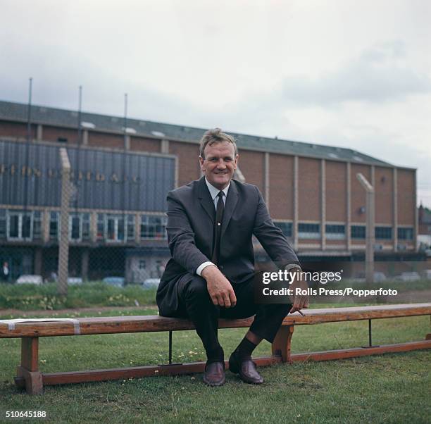 English ex footballer and manager of Leeds United, Don Revie pictured sitting on a bench and smoking a cigar outside Leeds United's Elland Road...