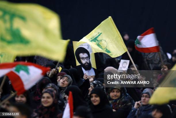 Supporters wave the flag of Lebanon and the Shiite movement Hezbollah alongside a poster of former Hezbollah leader Abbas al-Mussawi as they watch...