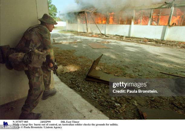 24Sep99 Dili, East Timor While A Large Fire Burns Out Of Control, An Australian Solider Checks The Grounds For Militia.