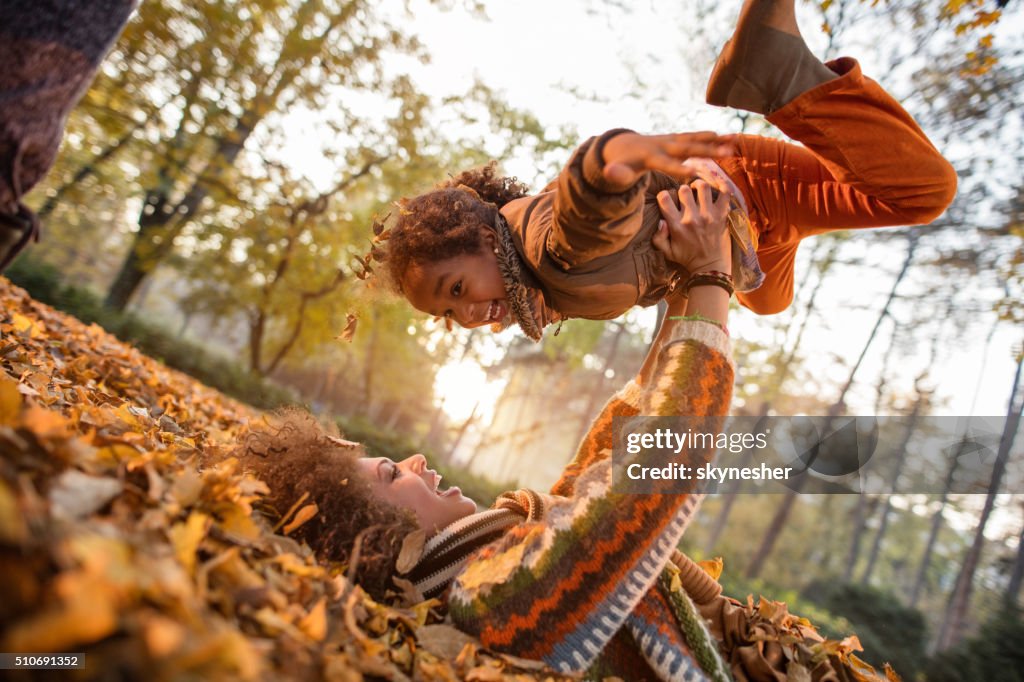 Happy African American mother playing with her daughter in nature.