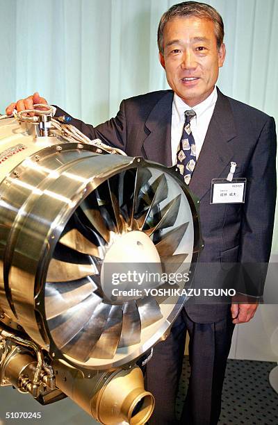 Japan's auto giant Honda Motor President Takeo Fukui displays the company's turbofan jet engine HF118, designed for light business jet plane, during...