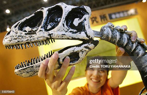 Tomomi Adachi , exhibition guide, assembles a model skelton of a "Deinonychus" as she explains about the dinosaur during a press preview of the...