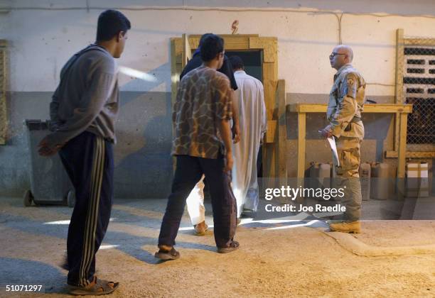 Army Sergeant Dale Wall from Holland, Michigan of the 391st Military Police Battalion watches as prisoners are moved into a cell as they wait to be...