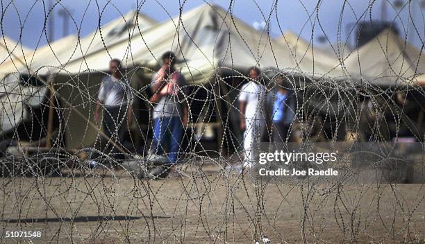 Prisoners stand next to the tents in which they are housed at the Abu Ghraib prison on July 15, 2004 west of Baghdad, Iraq. Many of the prisoners...