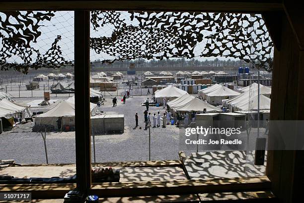 Prisoners mill around in a common area where they are housed in tents, in the Abu Ghraib prison on July 15, 2004 west of Baghdad, Iraq. Many of the...